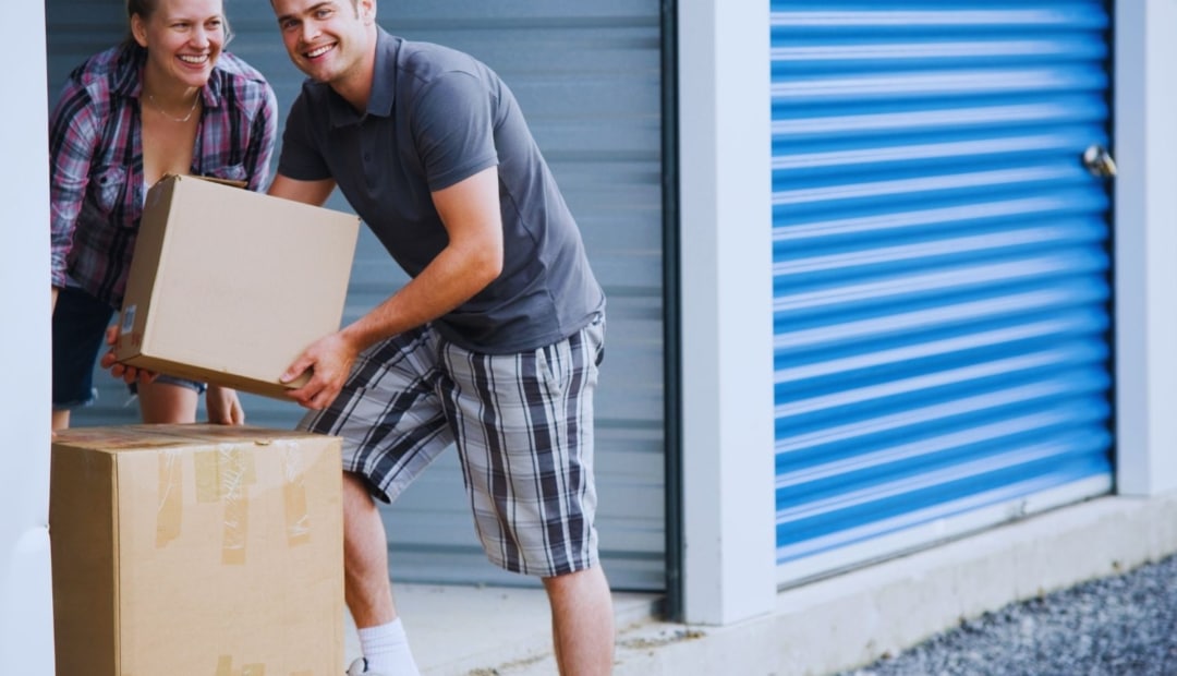 Couple transportant des cartons vers un box de stockage