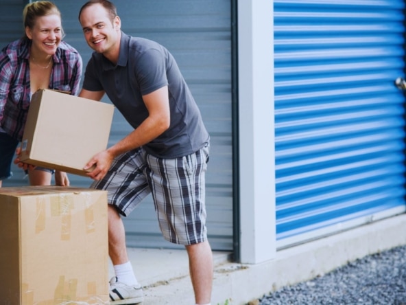 Couple transportant des cartons vers un box de stockage