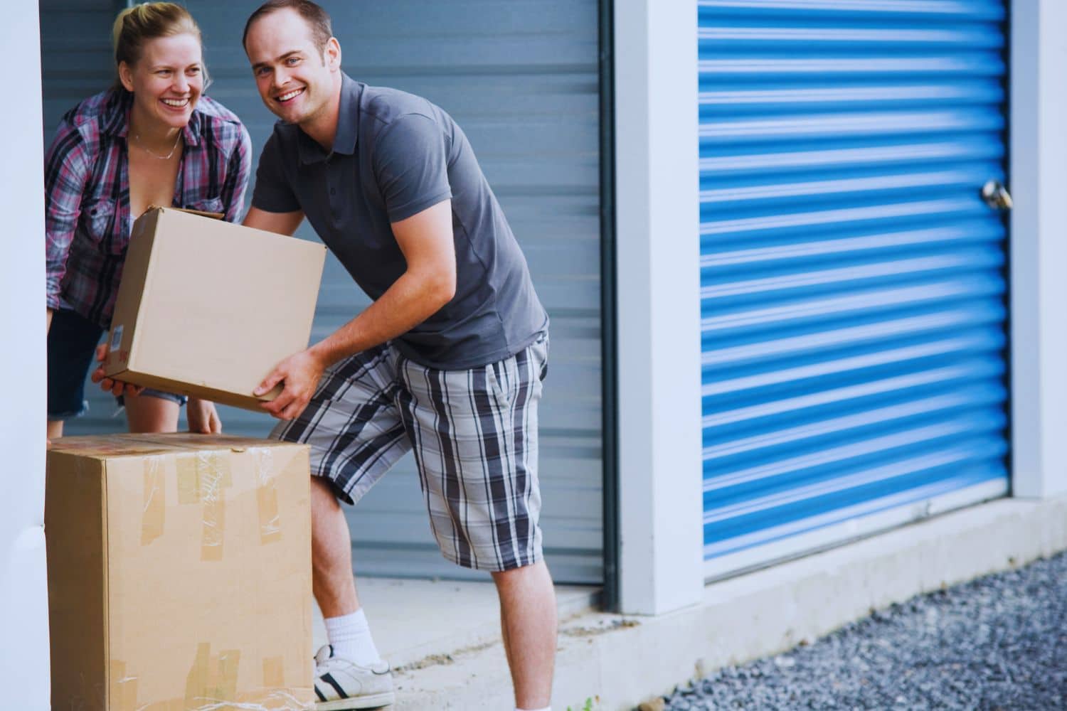 Couple transportant des cartons vers un box de stockage
