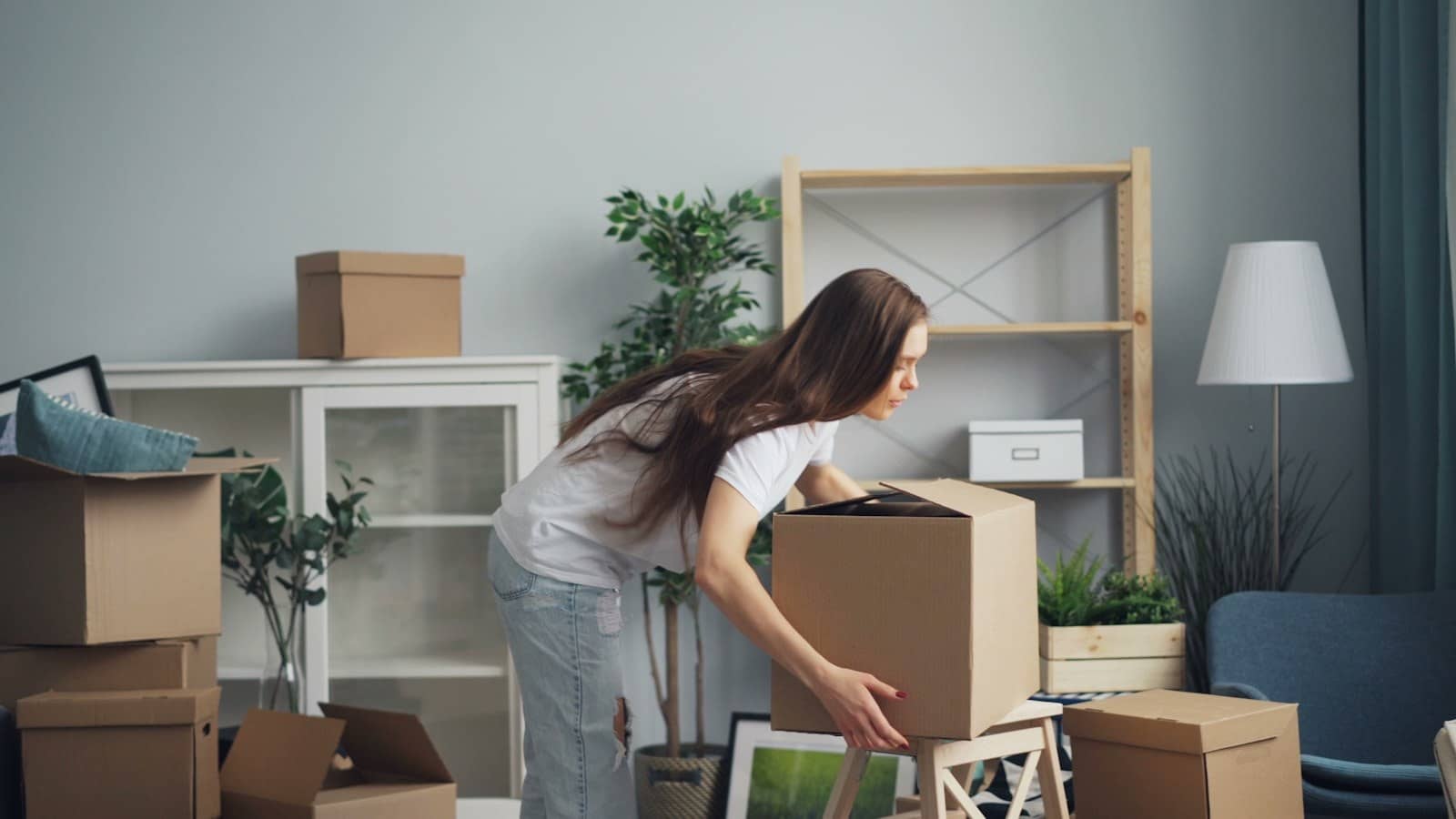 Femme préparant des cartons dans un salon avant un déménagement