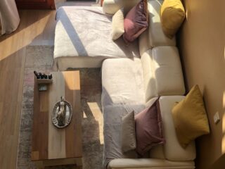 Petit salon lumineux avec canapé modulable, table basse et lumière naturelle