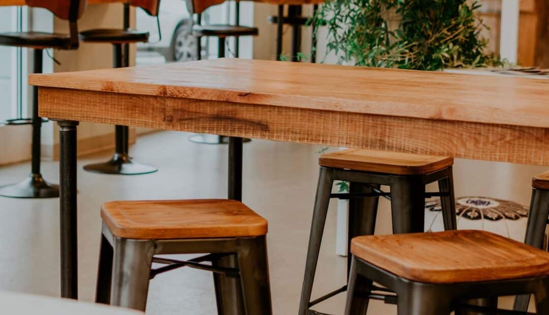 Table en bois massif et tabourets en métal dans un intérieur industriel